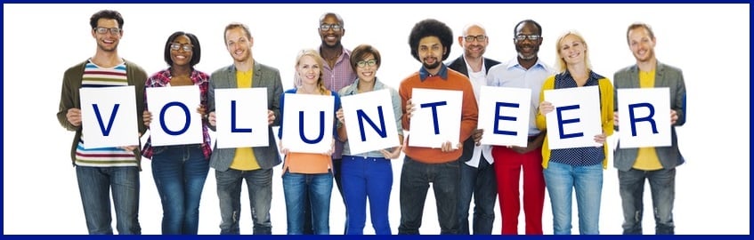 A diverse group of people holding up large letters that spell "VOLUNTEER".